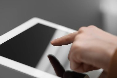 Bulanık arkaplanda modern tablet kullanan kadının yakın görüntüsü