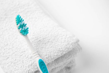 Açık mavi diş fırçası ve beyaz arka planda terry havlusu, yakın plan.