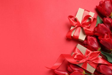 Kırmızı arka planda güzel hediye kutuları ve lale çiçekleri var. Metin için boşluk