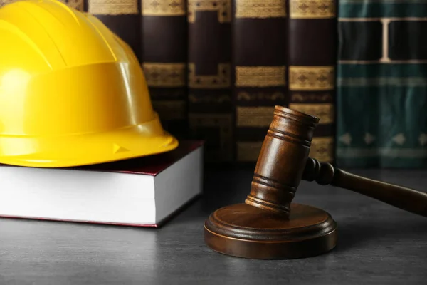 Labour, construction and land law concepts. Judge gavel, books with protective helmet on grey table