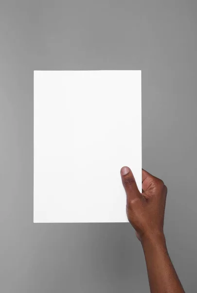 African American Man Holding Sheet Paper Grey Background Closeup Mockup — Stockfoto