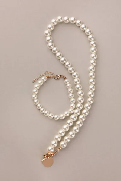 米色背景的精致珍珠项链和手镯 顶视图 — 图库照片