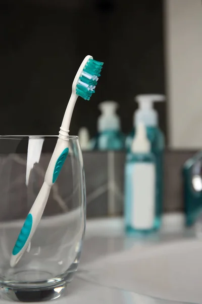 stock image Light blue toothbrush in glass holder on washbasin