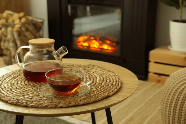 居心地の良いリビングルームでスタイリッシュな暖炉の近くのコーヒーテーブルの上にティーポットと飲み物のカップ インテリアデザイン — ストック写真
