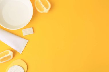 Limonlu yüz yıkama, taze narenciye meyveleri ve sarı arka planda kişisel bakım ürünleri.