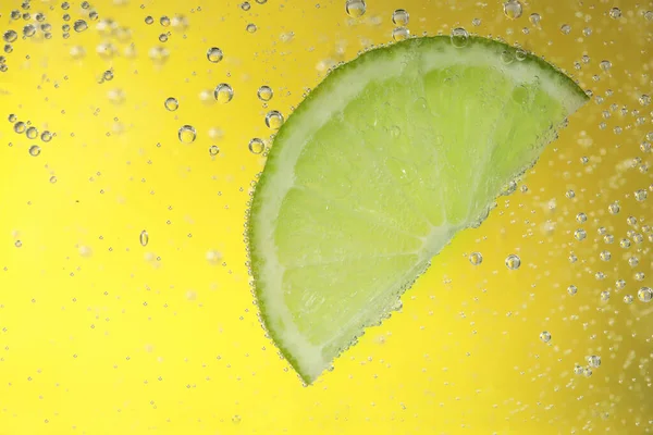 Saftig Lime Skiva Läsk Vatten Mot Gul Bakgrund Närbild — Stockfoto