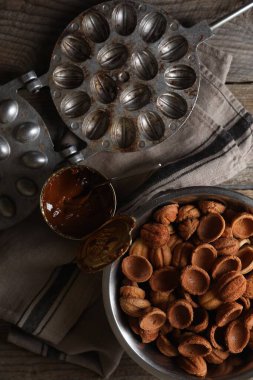 Ceviz şeklinde kurabiye yapıyorum. Pişmiş hamur, karamelize edilmiş süt ve ahşap masada küflenmiş, düz uzanmış.