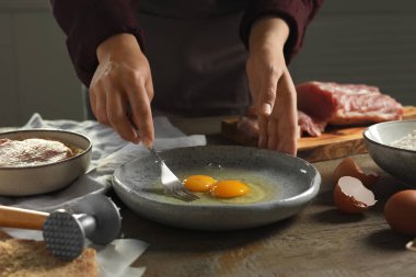 Ahşap masada şnitzel pişiren kadın, yakın plan.