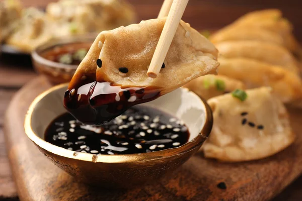 stock image Taking delicious gyoza (asian dumpling) with soy sauce at table, closeup