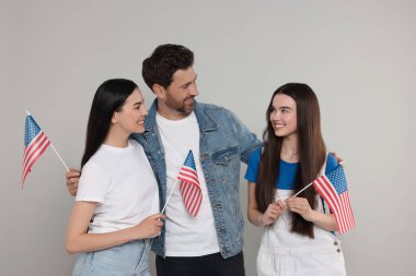 4 Temmuz - ABD 'nin Bağımsızlık Günü. Gri arka planda Amerikan bayrakları olan mutlu bir aile.