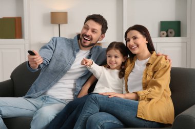Evde film izleyen mutlu bir aile. Babam uzaktan kumandayla televizyon kanallarını değiştiriyor.