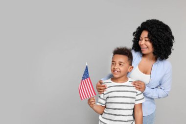 4 Temmuz - ABD 'nin Bağımsızlık Günü. Açık gri arka planda Amerikan bayrağı olan mutlu kadın ve oğlu, mesaj için yer