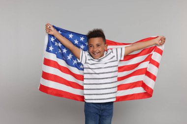 4 Temmuz - ABD 'nin Bağımsızlık Günü. Açık gri arka planda Amerikan bayrağı taşıyan mutlu çocuk.