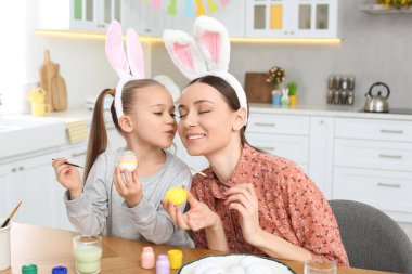 Anne ve tatlı kızı mutfakta paskalya yumurtası boyuyor.