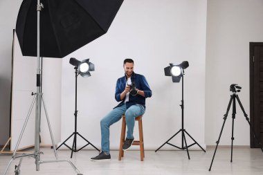 Modern fotoğraf stüdyosunda kamerası olan genç profesyonel fotoğrafçı.