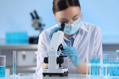 Laboratuvarda mikroskop ve test tüpleriyle çalışan bilim adamları.
