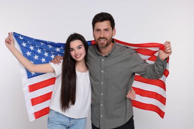 4 Temmuz - ABD 'nin Bağımsızlık Günü. Mutlu baba ve kızı beyaz arka planda Amerikan bayrağı taşıyorlar.