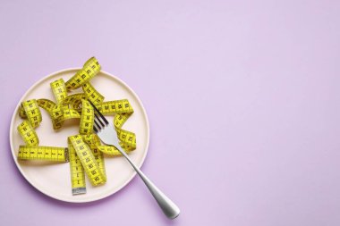 Menekşe arkaplanındaki çatal ve şerit ölçülüyor, üst görünümde metin için boşluk var. Kilo verme konsepti