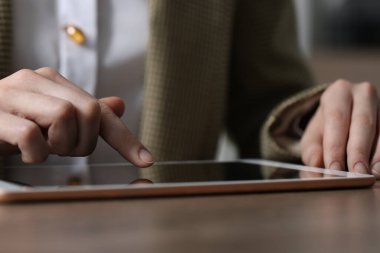 Masada arka planda modern tablet kullanan bir kadının yakın görüntüsü