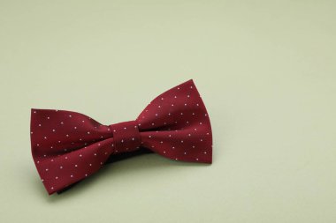 Soluk yeşil arkaplanda benek desenli koyu kırmızı papyon, metin için boşluk