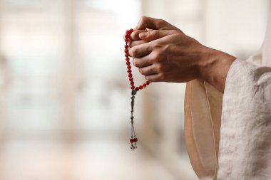 Misbaha 'lı Müslüman bir adam bulanık arka planda dua ediyor, yakın plan. Metin için boşluk