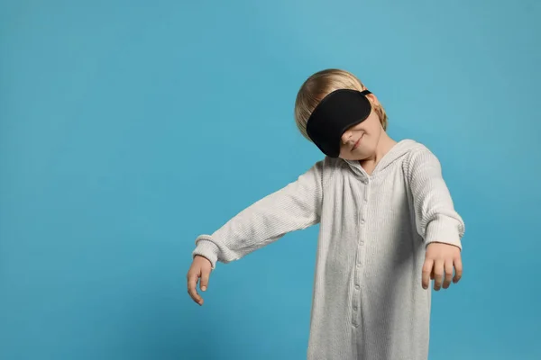 stock image Boy in pajamas and sleep mask sleepwalking on light blue background, space for text