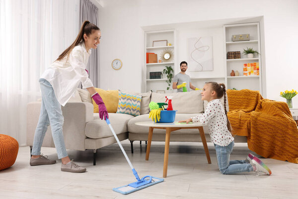 Spring cleaning. Happy family tidying up together at home