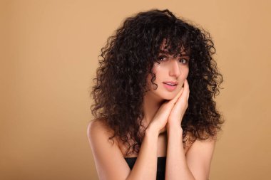Bej arka planda uzun kıvırcık saçlı güzel bir genç kadın. Metin için boşluk