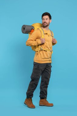 Açık mavi arka planda sırt çantalı bir adam. Etkin turizm