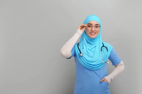 穆斯林妇女 头戴头巾 身穿医疗制服 带听诊器 浅灰背景 文字空间 — 图库照片