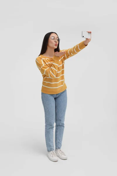 Jovem Mulher Tomando Selfie Com Smartphone Soprando Beijo Fundo Branco — Fotografia de Stock