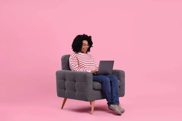 Ευτυχισμένη Νεαρή Γυναίκα Φορητό Υπολογιστή Κάθεται Στην Πολυθρόνα Ροζ Φόντο — Φωτογραφία Αρχείου