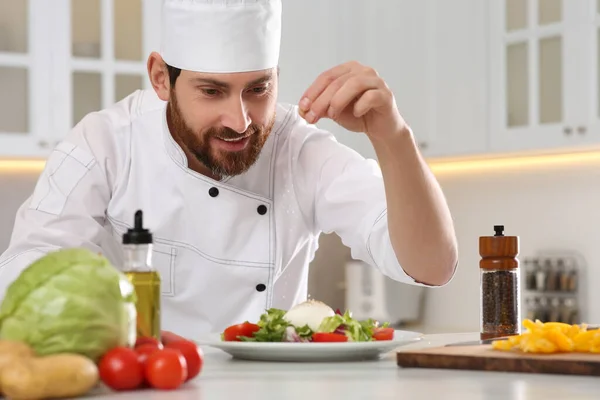 stock image Professional chef salting delicious salad at marble table in kitchen