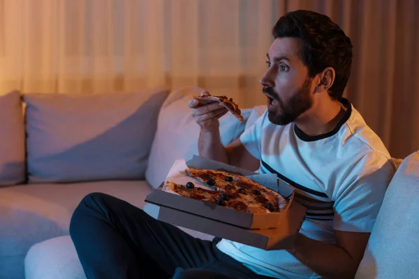 男人晚上在沙发上看电视时吃披萨 坏习惯 — 图库照片