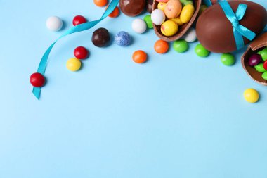 Lezzetli çikolatalı yumurtalar ve açık mavi arka planda farklı şekerler içeren kompozisyon. Metin için boşluk