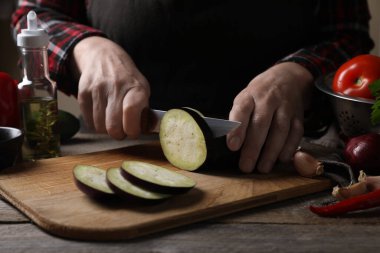 Lezzetli ratatouille pişiriyorum. Ahşap masada patlıcan kesen kadın, yakın plan.