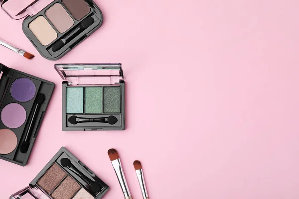 stock image Beautiful eye shadow palettes and brushes on pink background, flat lay. Space for text