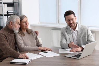 Ahşap masa içerisindeki emeklilik planıyla ilgili danışmanlık yapan yaşlı çift.