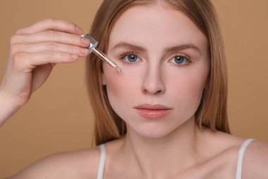 Esaslı yağı açık kahverengi arka planda yüzüne süren kadın