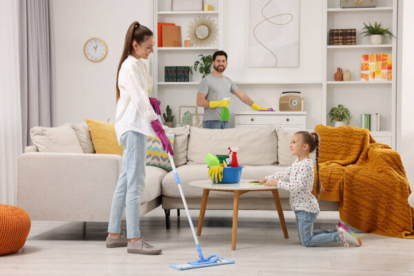 Spring cleaning. Happy family tidying up together at home