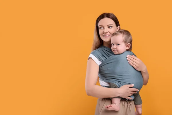 Moeder Houdt Haar Kind Babyverpakking Oranje Achtergrond Ruimte Voor Tekst — Stockfoto