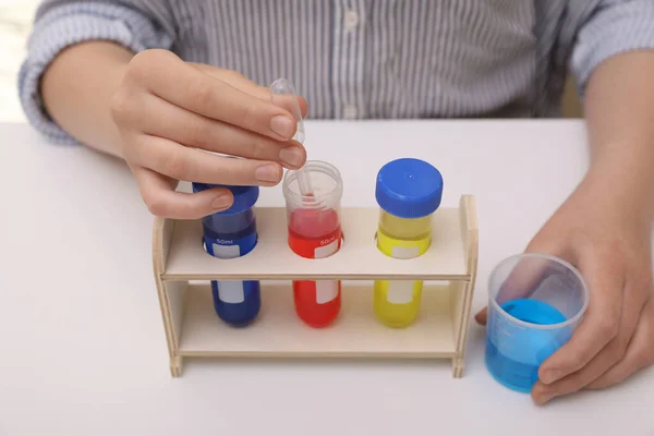 女孩与五颜六色的液体在试管和烧杯在室内白桌 儿童化学实验集 — 图库照片