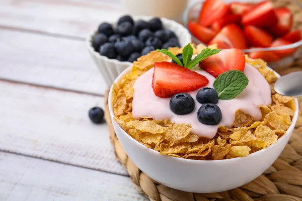 美味的脆玉米片 酸奶和新鲜的浆果在白色木制桌子的碗里 特写与文字的空间 健康早餐 — 图库照片