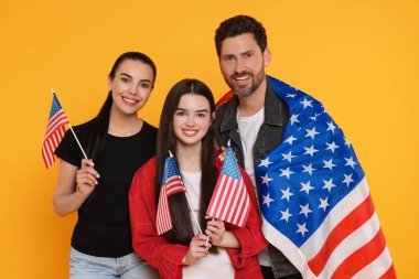 4 Temmuz - ABD 'nin Bağımsızlık Günü. Sarı arka planda Amerikan bayrakları olan mutlu bir aile