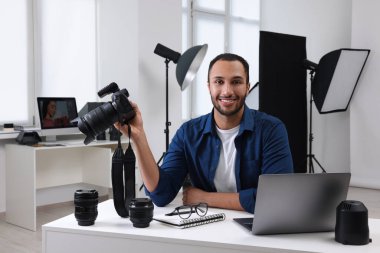 Modern fotoğraf stüdyosundaki masada kamerası olan genç profesyonel fotoğrafçı.