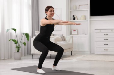 Sabah egzersizi. Evde çömelmiş mutlu bir kadın, mesaj için yer var.