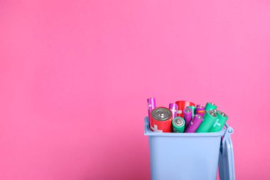 Pembe arka plandaki geri dönüşüm kutusunda birçok kullanılmış pil var. Metin için boşluk