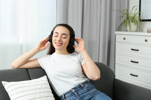 Glückliche Frau Mit Kopfhörer Genießt Musik Auf Weichem Sofa Hause — Stockfoto