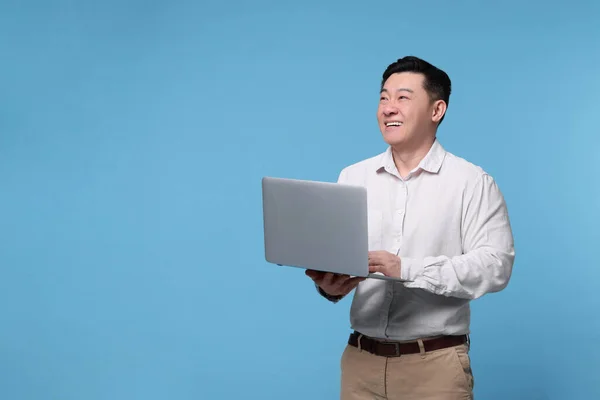 明るい青の背景にノートパソコンを持つ幸せな男 テキストのためのスペース — ストック写真