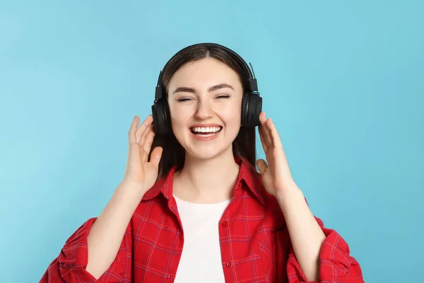 明るい青の背景で音楽を楽しむヘッドフォンの幸せな女性 — ストック写真